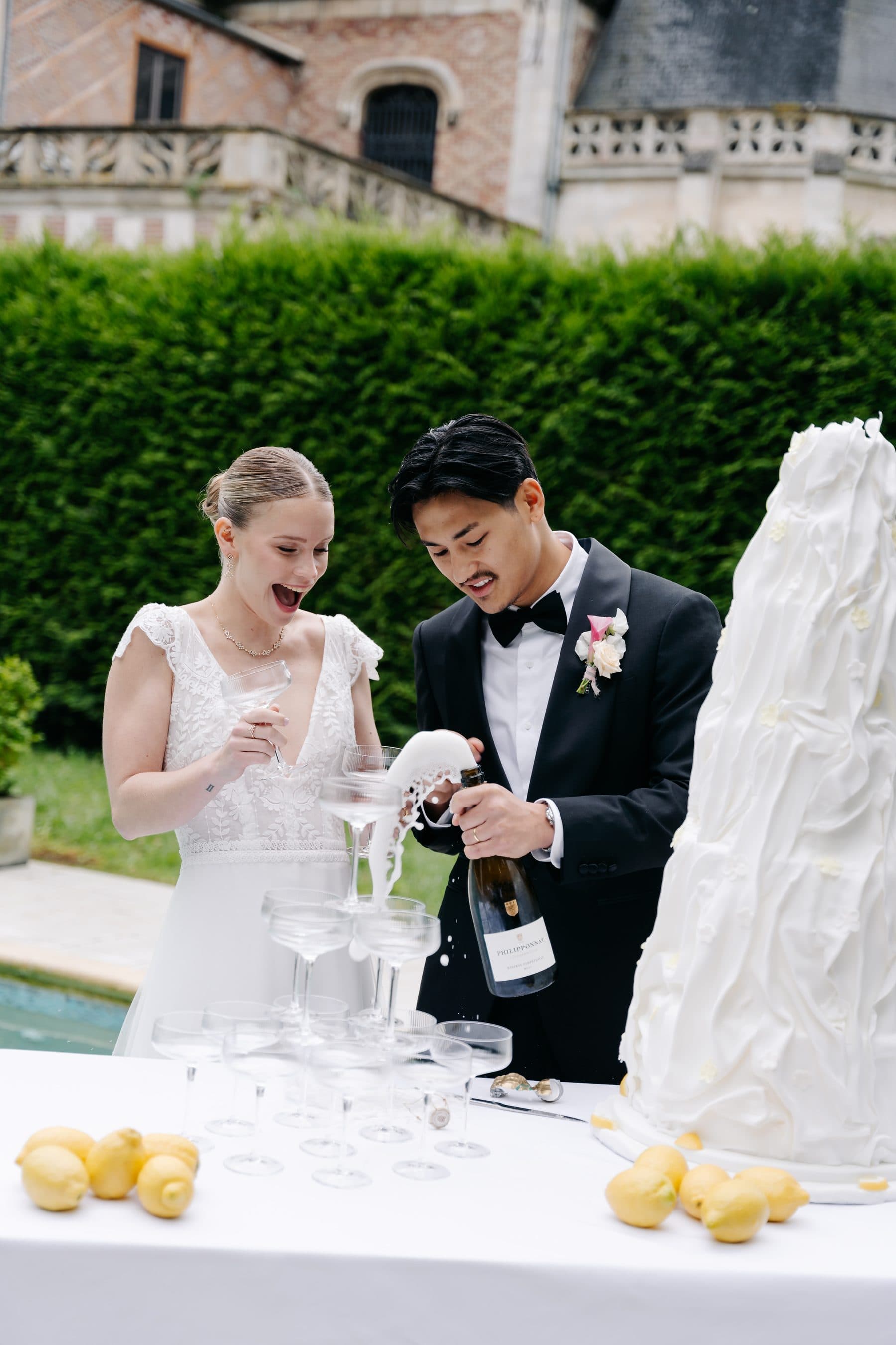 Les mariés servant le champagne devant la pièce montée, au bord de la piscine