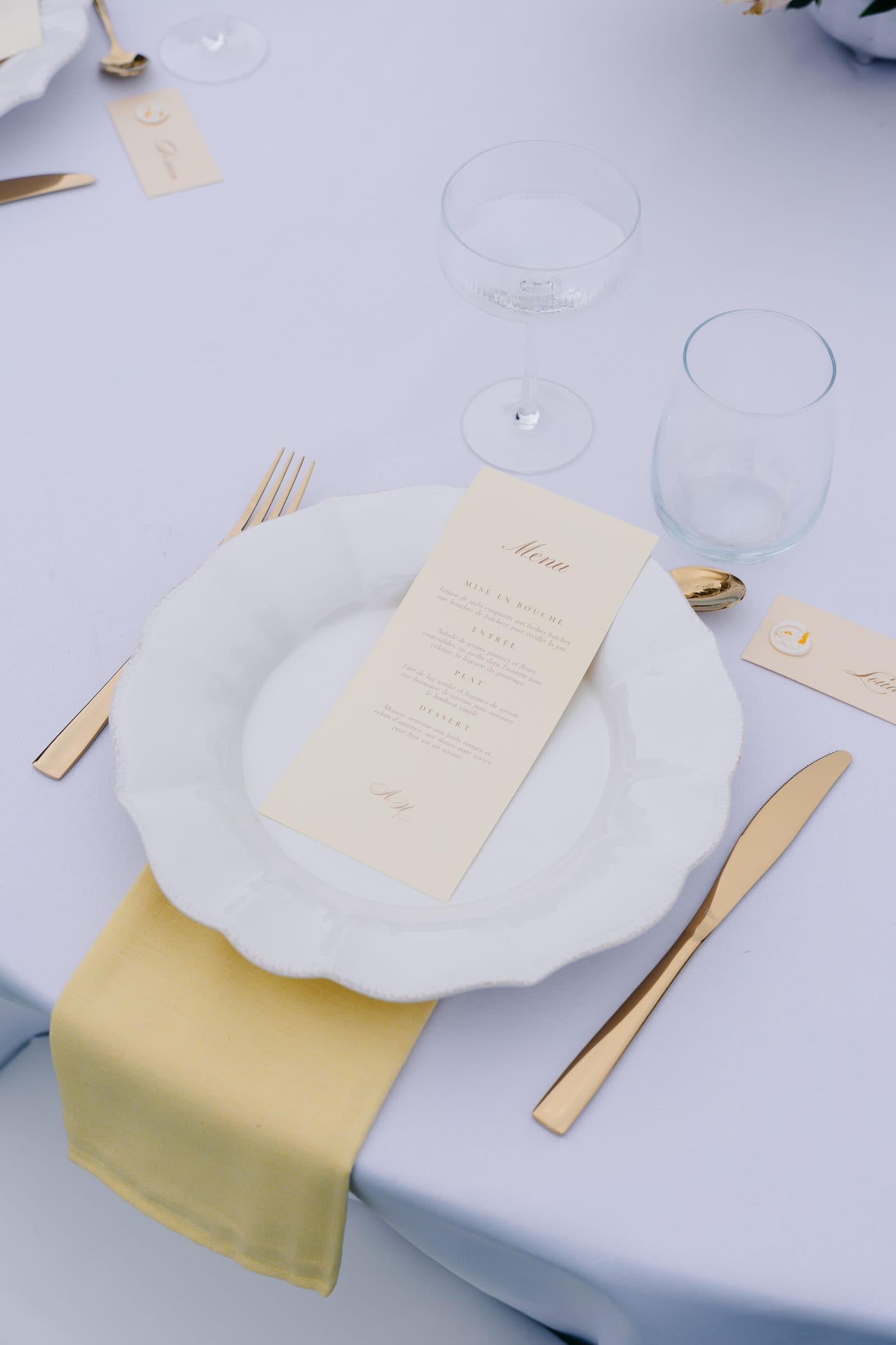 Couvert dressé avec menu imprimé, serviette dorée et couverts
