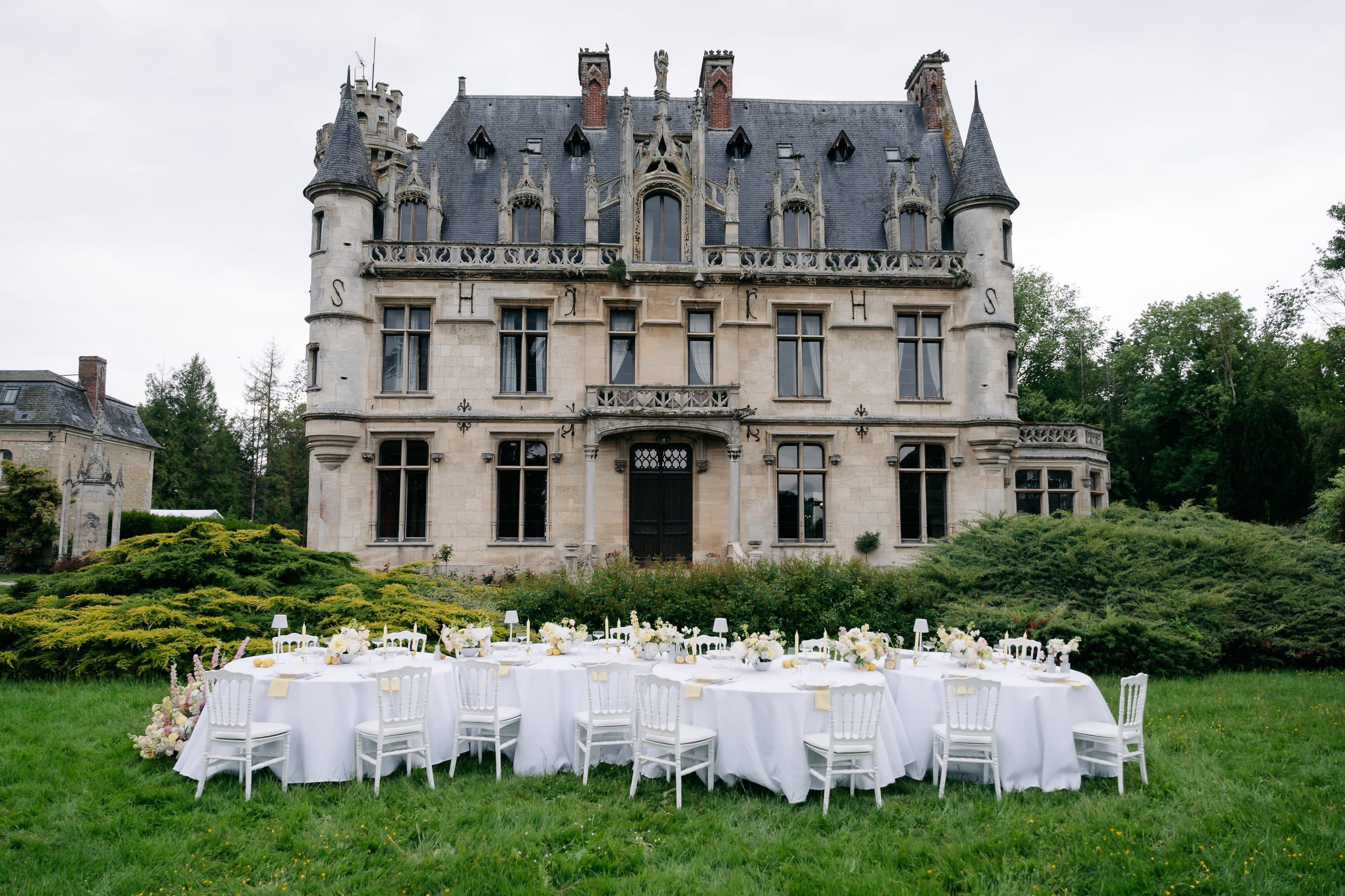 Longue table dressée devant la façade du château pour un dîner de mariage