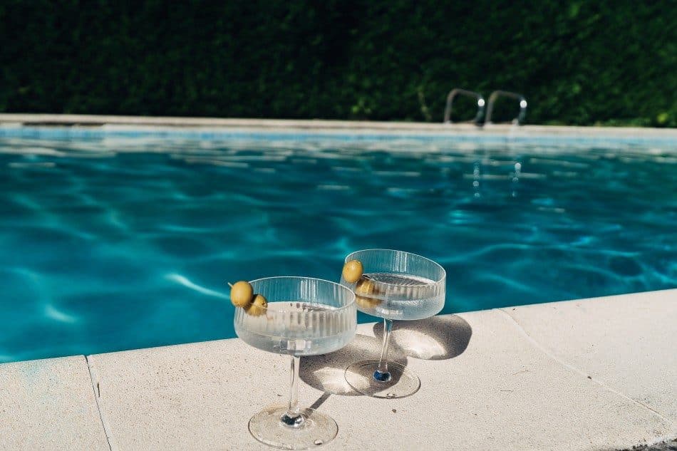 Deux coupes de champagne posées au bord de la piscine