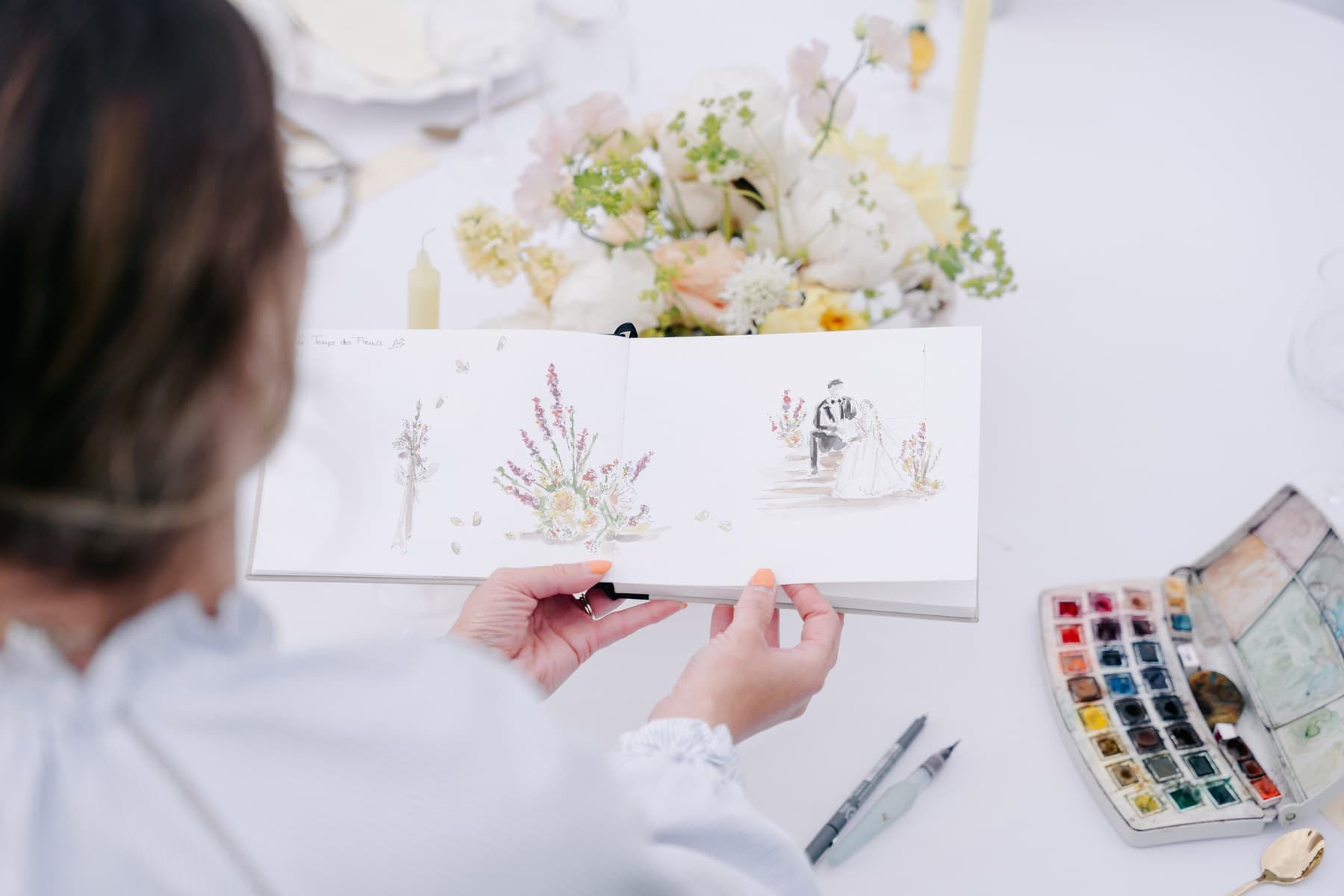 L'illustratrice dessinant en direct, aquarelle et carnet de croquis, sur une table dressée du domaine