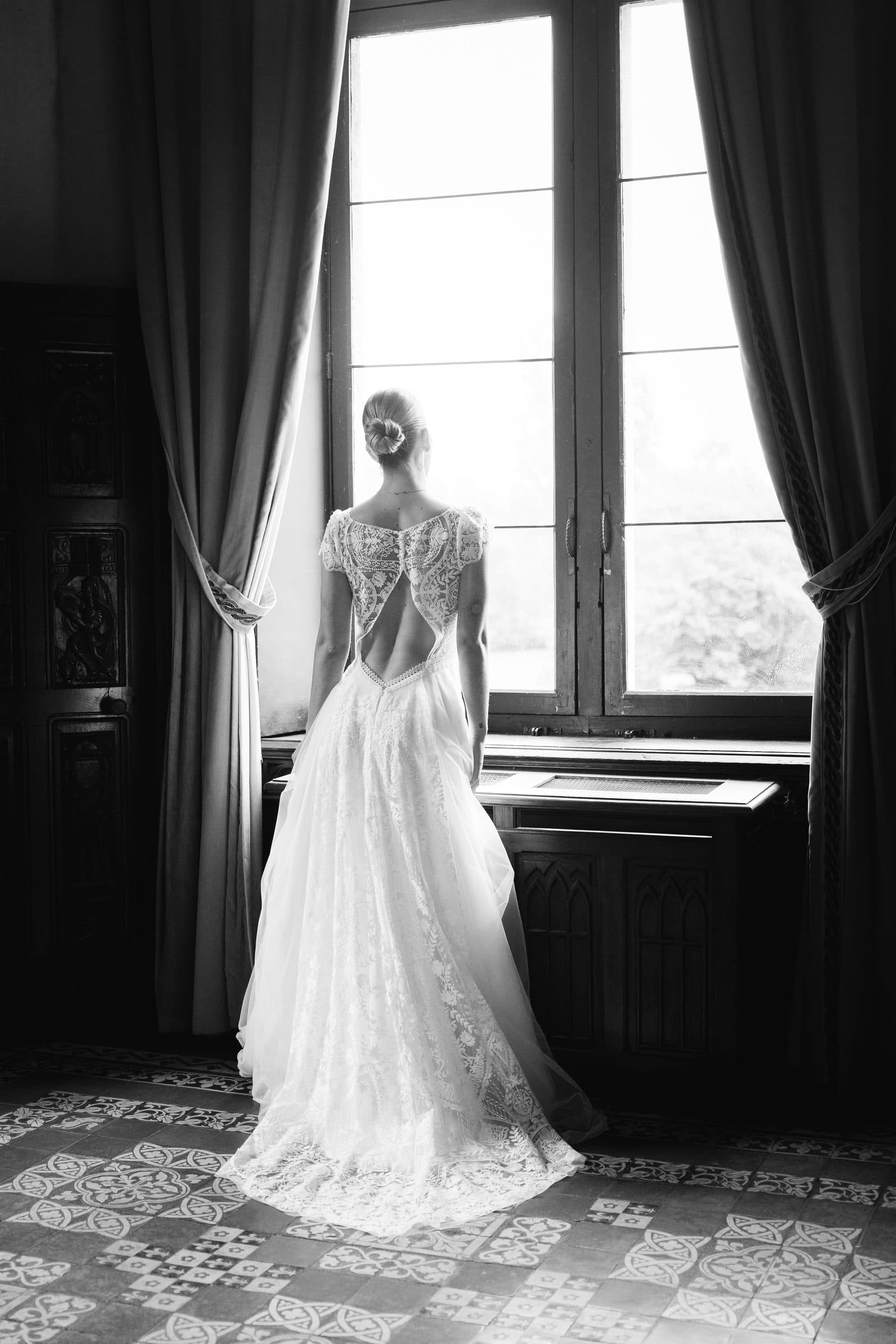 Silhouette d'une mariée à contre-jour devant une haute fenêtre
