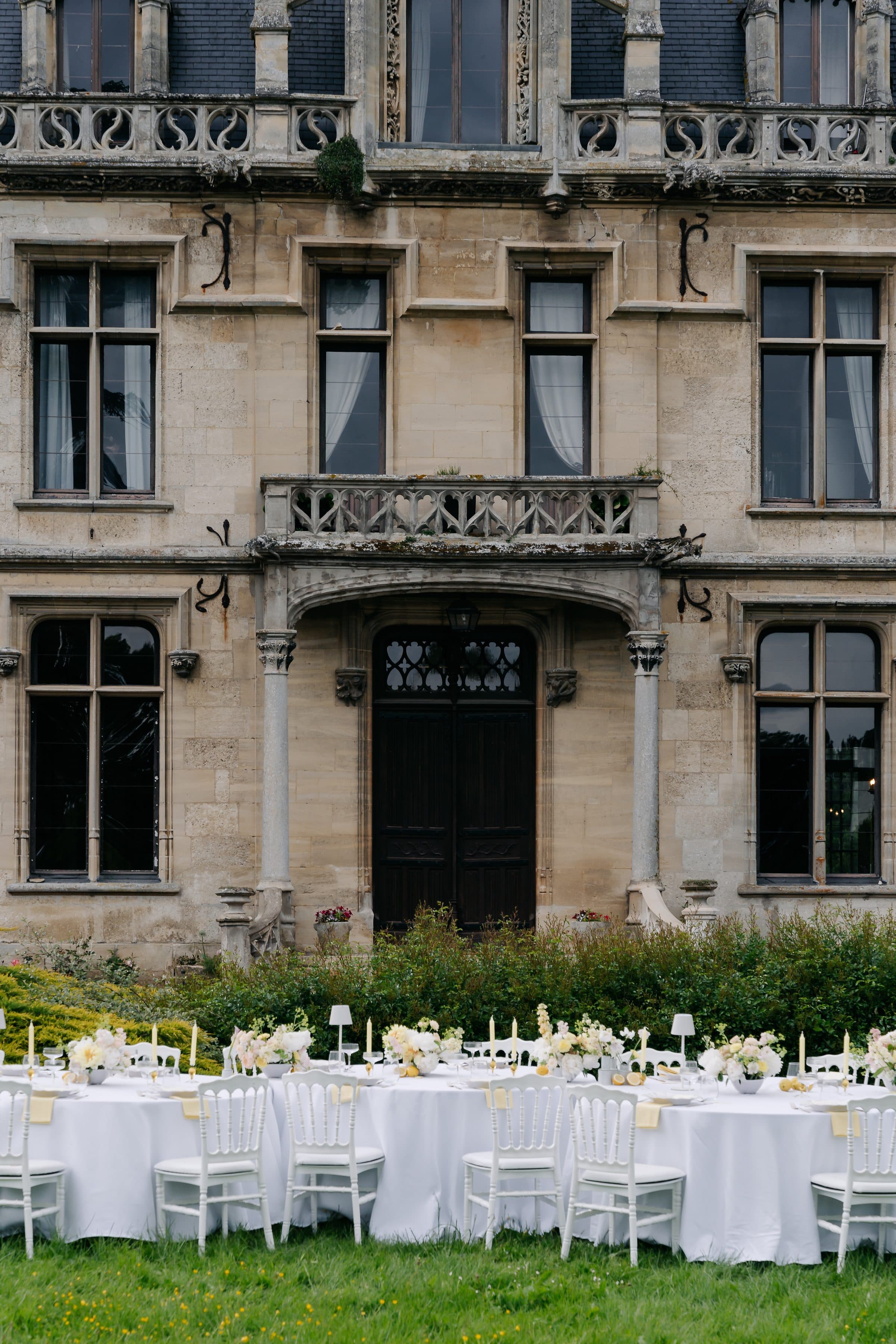 Longues tables dressées devant la façade du château pour un dîner de mariage