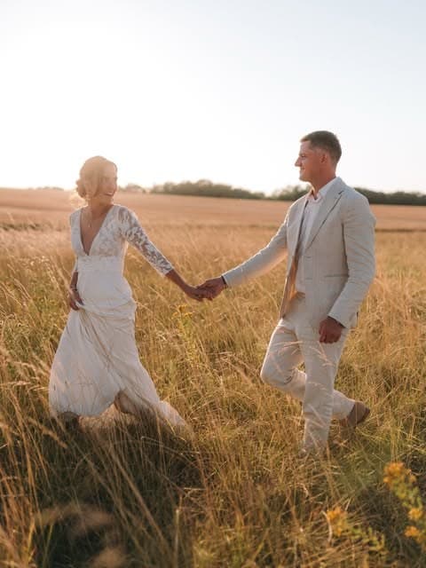 Mariage orchestré par D-Day : les mariés main dans la main dans un champ, à l'heure dorée