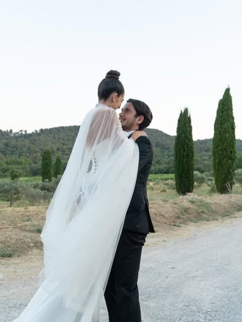 Photographie de mariage signée Romane Texier, les mariés et le voile au coucher du soleil