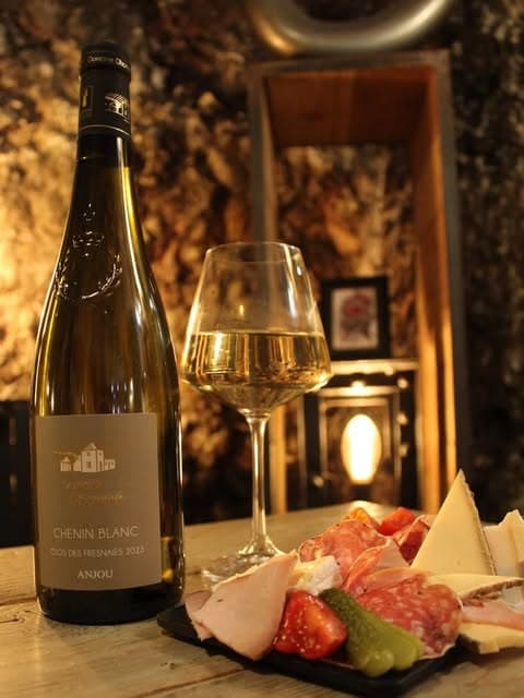 Bouteille de vin blanc, verre servi et planche de charcuterie chez Le Rouge qui Tache